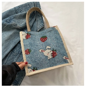 Close-up of woven light blue tote bag with white rabbit and strawberry cartoon patterns