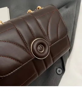 Detailed view of the dark brown quilted leather texture and gold chain strap of the bag