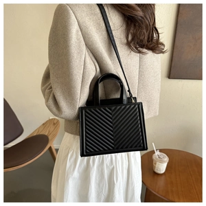 Detailed view of black quilted crossbody bag with adjustable strap and top handles