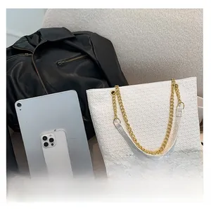 Bolso tote acolchado blanco con cadena dorada junto a tablet para comparar el tamaño