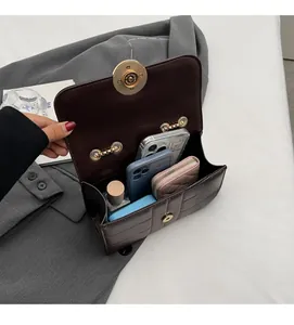 Detailed top view of brown quilted bag interior holding phones, wallet and perfume