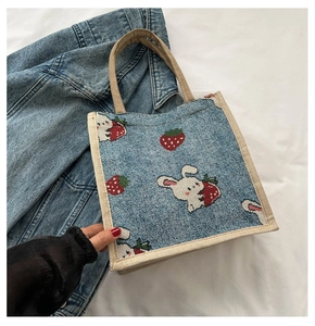 Detail of blue denim tote bag with cartoon rabbit and strawberry woven patterns