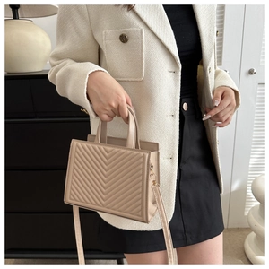 Detail of apricot quilted tote bag featuring gold hardware and removable shoulder strap