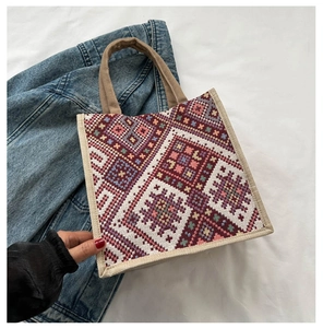 Detailed weave of ethnic geometric pattern on large jute tote bag over denim jacket