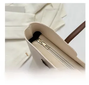 Dettaglio ravvicinato della cerniera in metallo dorato sulla borsa tote in ecopelle beige