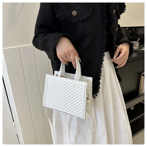 Close-up of white leather tote bag with V-quilted pattern and elegant stitching details