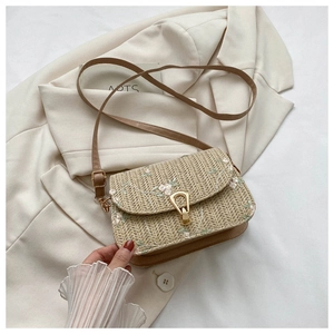 Detailed shot of straw saddle bag with delicate floral embroidery and gold metal lock