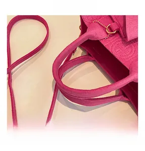 Vue détaillée du sac en feutre rose montrant le logo en relief et la bandoulière