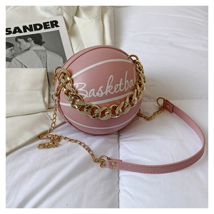 Pink basketball shape bag with white lettering and gold chain strap on white fabric