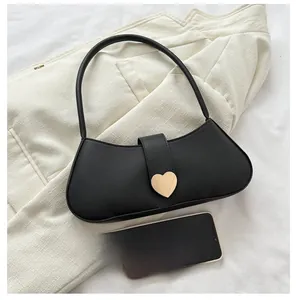 Close-up of black crescent underarm bag featuring a golden heart buckle and slim strap