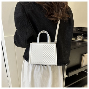 Detail of white quilted tote bag with V-shaped stitching and slim shoulder strap
