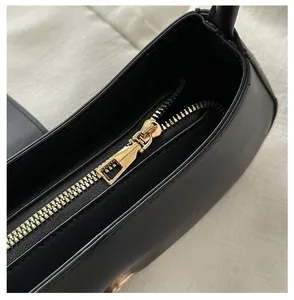 Detail of smooth gold metal zipper and black leather texture on stylish crossbody bag