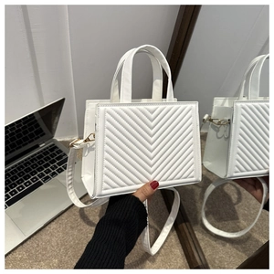 Detail of white V-quilted faux leather handbag showing elegant stitching and gold hardware