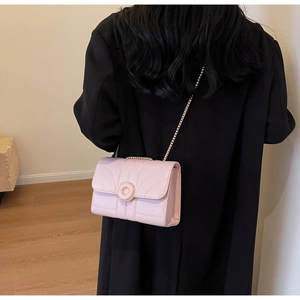 Rear view of a model wearing a pink quilted chain crossbody bag with metal buckle