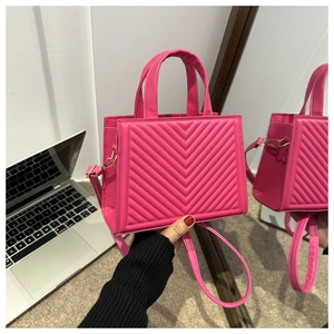 Close-up of pink quilted crossbody bag handle with metal buckle and chevron pattern