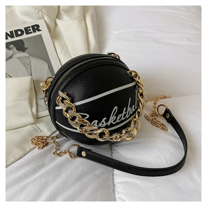 Detail of black basketball-shaped PU leather crossbody bag with white stitching and gold chain