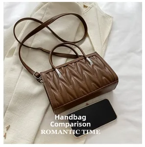 Brown quilted leather handbag with V-shaped pleats shown next to a smartphone for size scale
