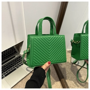 Detail of green quilted tote bag showing V-shaped stitching and gold-tone hardware