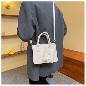 Détail du sac à main en cuir blanc gaufré avec sa mini pochette enveloppe assortie