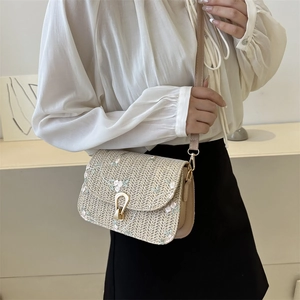 Straw saddle bag with pink floral embroidery and leather strap worn by a model