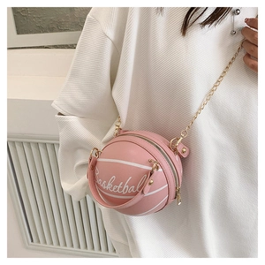 Sac bandoulière rose en forme de basket avec chaîne dorée porté sur un pull blanc gaufré