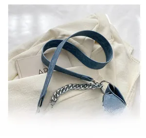 Detail of blue textured underarm bag featuring wide strap and silver metal chain accessory