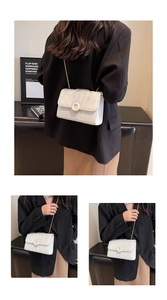 Close-up of white quilted crossbody bag with V-shaped stitching and gold chain
