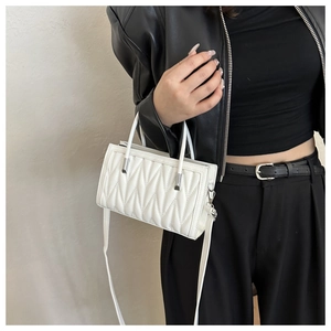 Detail of white quilted rectangular handbag with silver hardware and shoulder strap