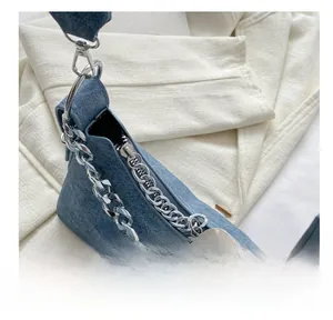 Detail of silver smooth zipper and textured denim fabric on a stylish chain shoulder bag