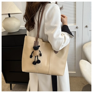 Dettaglio della grande borsa tote beige con manici marroni e ciondolo a pecora