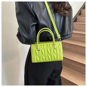 Fluorescent green quilted crossbody bag with textured rhombic patterns on black jacket