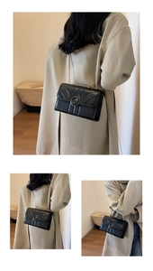 Close-up of minimalist black crossbody chain bag with geometric stitching and round clasp