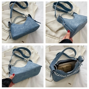 Detail view of denim texture half-moon bag with silver chain and wide shoulder strap