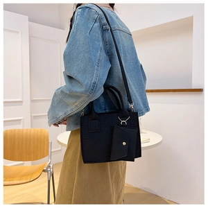 Détail du sac cabas noir gaufré avec sa pochette assortie porté par un mannequin