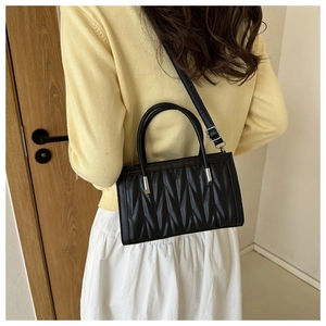 Detail of a black pleated leather handbag shown with crossbody strap on a model