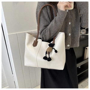 Dettaglio borsa tote in pelle bianca con manici marroni e ciondolo a forma di orso