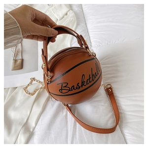 Detail of creative orange basketball shaped handbag with chain strap on white bedding