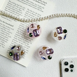 Close-up of four resin phone grips with colorful rhinestones and crystal gemstone inlay