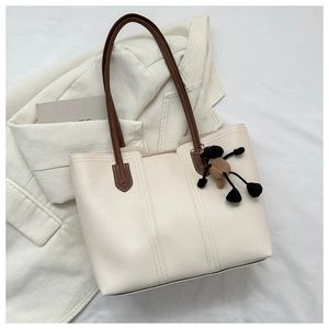 Dettaglio della borsa tote in pelle crema con cuciture verticali e tracolla marrone