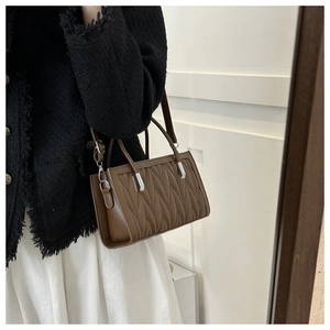 Close-up of brown chevron quilted handbag showing silver hardware and crossbody strap
