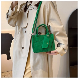 Détail du sac à main en feutre gaufré vert avec petite pochette sur trench-coat beige