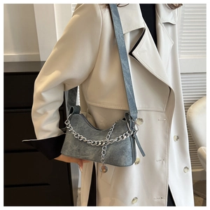 Detail of vintage denim blue crescent shoulder bag with chunky silver chain and metal charm