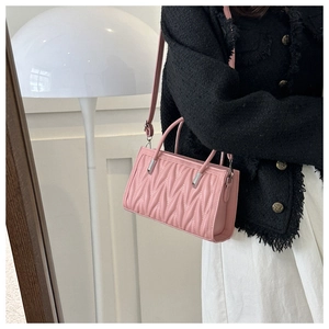 Detailed view of pink quilted PU leather handbag with V-shaped stitching and silver hardware