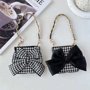 Detail view of houndstooth flip phone case with decorative bow and gold chain handle