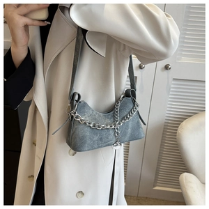 Detail view of a gray denim crescent bag with a silver chain and stylish shoulder strap