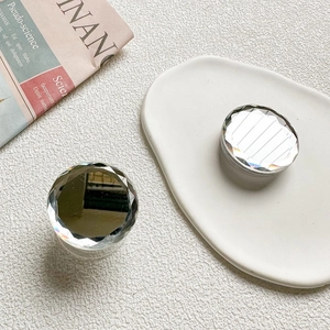 Macro view of silver faceted mirror cell phone sockets on a white minimalist plate