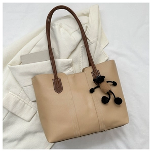 Dettaglio di borsa tote marrone chiaro con manici scuri e ciondolo a forma di pecora