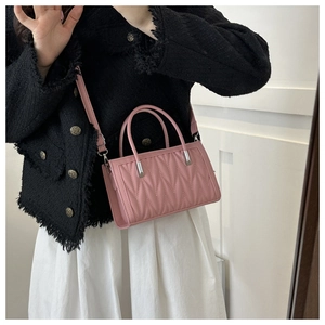 Detail of pink quilted handbag with V-shaped stitching and adjustable strap on model