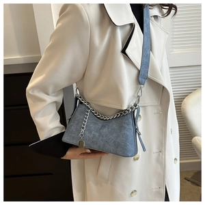 Blue denim textured shoulder bag with silver chunky chain and wide strap on model