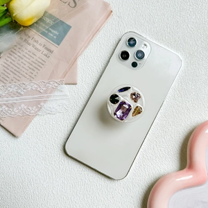 Phone grip with colorful rhinestone crystals on a white smartphone, 45-degree side view